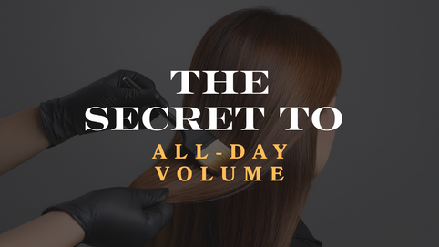 Hairstylist wearing black gloves lifting smooth brown hair, with the text “The Secret to All-Day Volume” overlaid on the image.