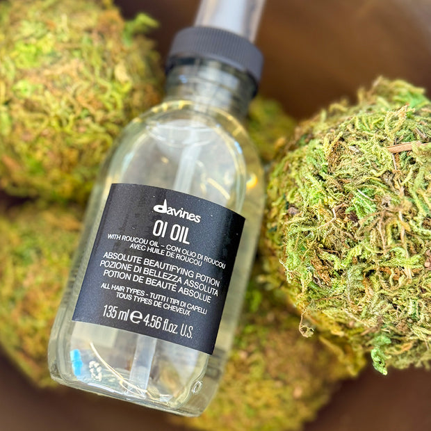 Bottle of Davines OI Oil with moss balls in the background