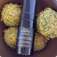 Davines OI Souffle hair product bottle on a background of green moss balls
